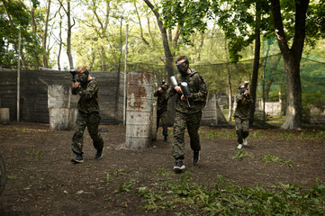Warriors in camouflage and masks playing paintball
