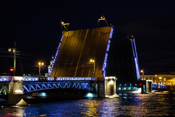 Plakat open palace bridge on the Neva River against the night sky with multicolored illumination and reflection in the water in Saint-Petersburg Russia