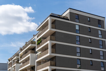 photograph of a modern building complex with many balconies in the middle of the city center. geometrically designed facade of a new building 