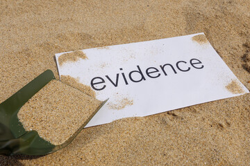 evidenceと書いた紙を砂に埋める
