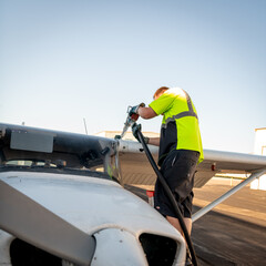 Fototapeta na wymiar Airport employee fills a small airplane with fuel
