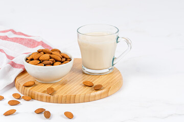 Almond milk in a glass with almond on a wooden table