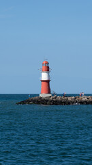 Red and white lighthouse on the Baltic Sea (inland sea) with cloudless sky and bright sunshine