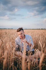 Naklejka na ściany i meble a village guy is sitting in a field in a white shirt and enjoying nature