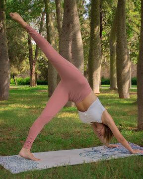 Vertical image of a recognizable young woman stretching after pilates exercise while making a video with her tablet for her social media. Concept of outdoor pilates.