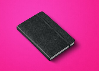 black closed notebook isolated on pink