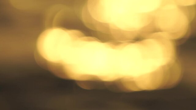 Delicate golden texture bokeh of glare on the water during sunset and dawn in slow motion 