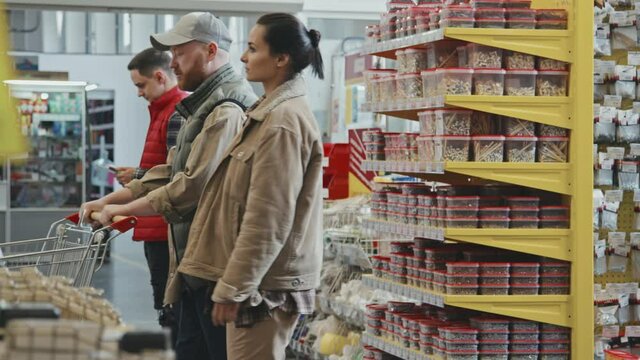 Slowmo PAN of couple with shopping cart walking through busy hardware store