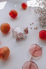 women's cosmetics, rose-colored glasses, peaches, apricots and flowers on a white background