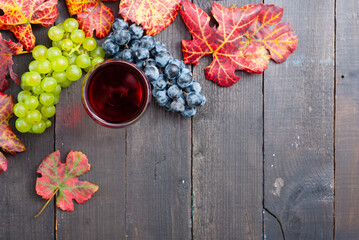 glass of red wine and grapes on black wooden table background