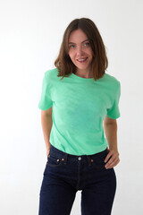 Obraz premium Positive female model wearing mint green color t shirt and jeans standing with hands on waist against white background and looking at camera