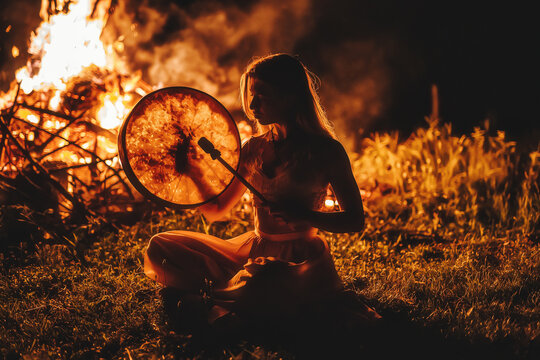 beautiful shamanic girl playing on shaman frame drum in the nature.