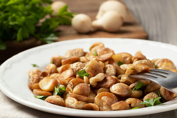 Fried puffball mushrooms on a white plate with a fork. Fried mushroom ready dish
