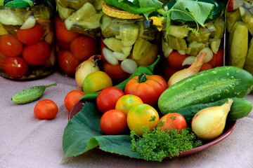 Preserves vegetables in glass jars on the table in summer garden. glass jars with various vegetables. Marinated food.Jars of pickled vegetables in the garden.