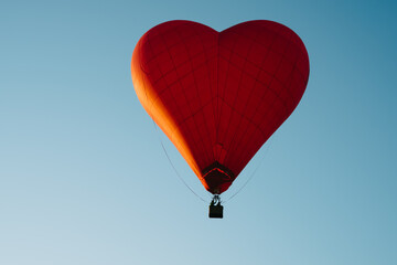 Fototapeta premium A red balloon in the shape of a heart flew into the sky. Valentine's Day.
