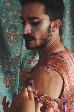 Portrait of queer young man with full face drag makeup & turkish anatolian nomad culture traditional clothing ripped apart