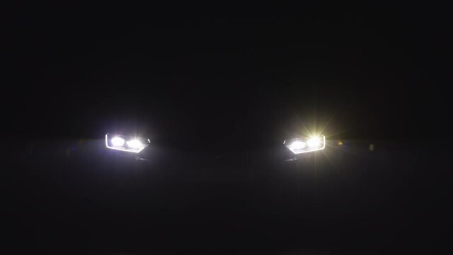 Car headlight blinking in Dark. Sports car Headlight. Shot of blinking headlights in car. LED Light New Luxury Car. Car emergency light signal, warning sign. Nobody around to help