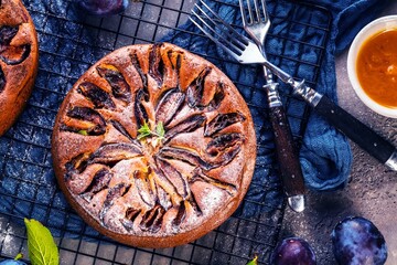 rustic plum cake on dark background , top view
