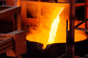 bright pouring molten metal from the furnace into the melting pot - Powered by Adobe