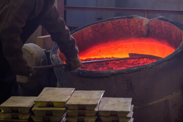 a foundry worker cleans the red-hot metal in the boiler so that it all goes to work