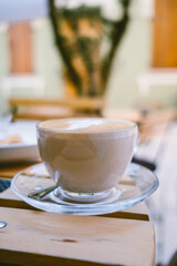 Сoffee in transparent glass cup on wooden table. Side view. Outdoor cafe. 