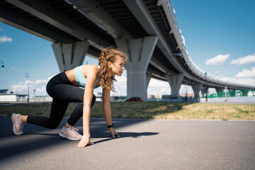 Fototapeta premium A strong, confident athlete, a runner leads a healthy lifestyle. Exercises stretching muscles for fitness are active. Fitness figure a woman trains on the street in the city.
