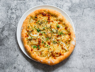 Homemade thin crispy flatbread pizza with gorgonzola and pear on a gray background, top view