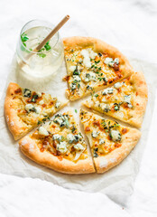 Gorgonzola pears thyme crispy pizza and a glass of white wine on a light background, top view