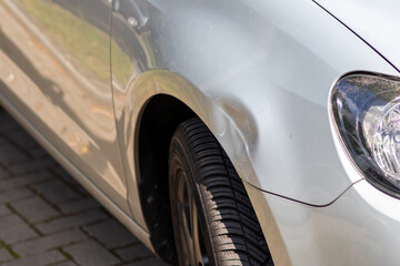 Dented car wing and fender with scratches and bumps after crash and car accident with hit-and-run...