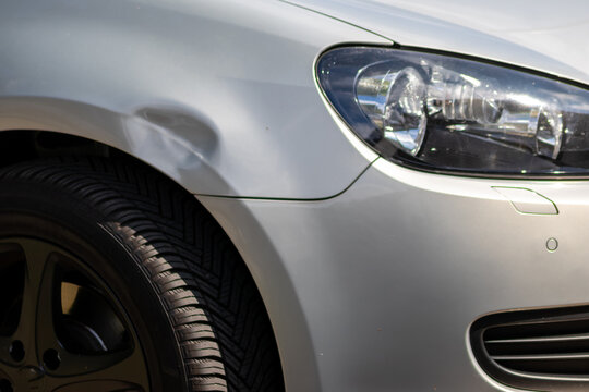 Dented car wing and fender with scratches and bumps after crash and car accident with hit-and-run driving and absconding shows need for car insurance and safety protection and mechanics garage service