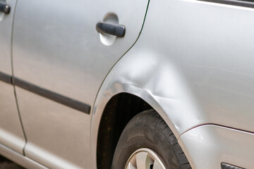 Dented car wing and fender with scratches and bumps after crash and car accident with hit-and-run...