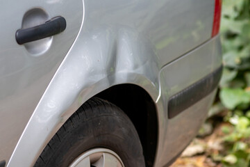 Dented car wing and fender with scratches and bumps after crash and car accident with hit-and-run...