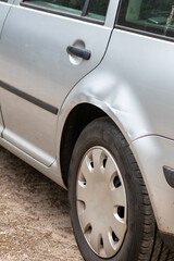Dented car wing and fender with scratches and bumps after crash and car accident with hit-and-run...