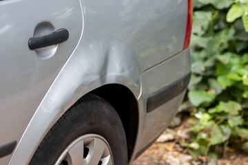 Dented car wing and fender with scratches and bumps after crash and car accident with hit-and-run...
