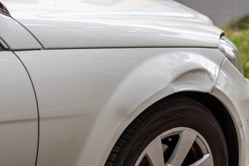 Dented car wing and fender with scratches and bumps after crash and car accident with hit-and-run...