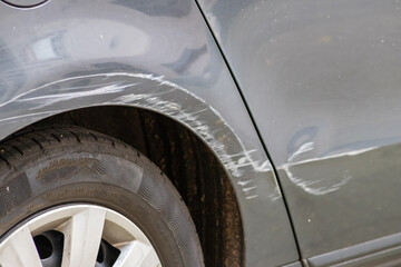 Dented car wing and fender with scratches and bumps after crash and car accident with hit-and-run...