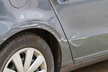 Dented car wing and fender with scratches and bumps after crash and car accident with hit-and-run...