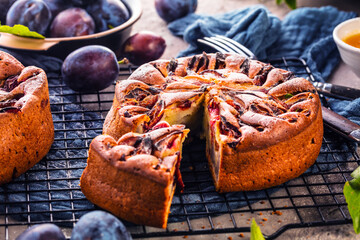 rustic plum cake on dark background , top view