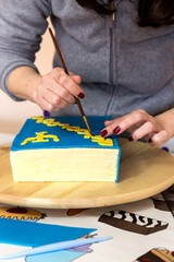 Fototapeta na wymiar Woman hands gluing fondant letters for cake decoration
