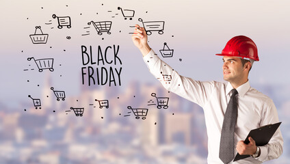 Young businessman with helmet drawing sale sign