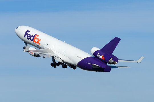 FedEx cargo airplane McDonnell Douglas MD-11F taking off from Anchorage Airport. Federal Express freighter aircraft MD11. Plane N588FE in steep climb.