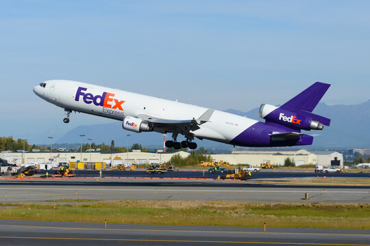 FedEx cargo aircraft McDonnell Douglas MD-11F taking off from Anchorage Airport. Federal Express freighter airplane MD11. Plane departing.