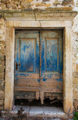 An old wooden door in a derelict stone residential building in the historic medieval village of Buje in Istria, Croatia
