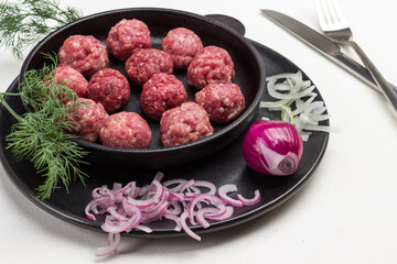 Raw meat balls in frying pan.