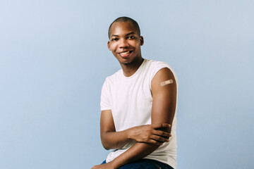 Young black man with a bandage . Black man showing his arm with a bandage for the coronavirus...