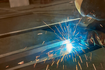 man processes metal with gas electric welding.