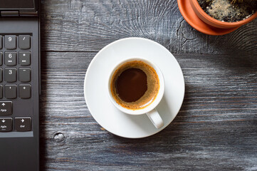 Cup of coffee, laptop, cactus on a wooden table, top view, flat lay. Workplace at home. Online Education.