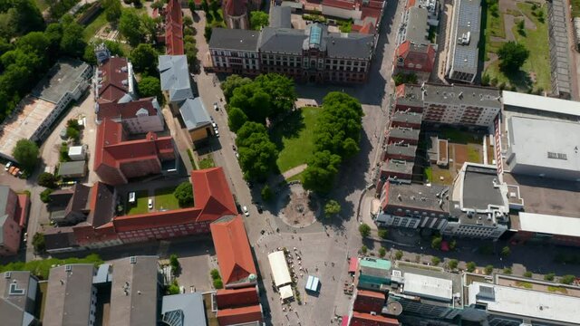 Ascending aerial footage of small square with trees in front of university building