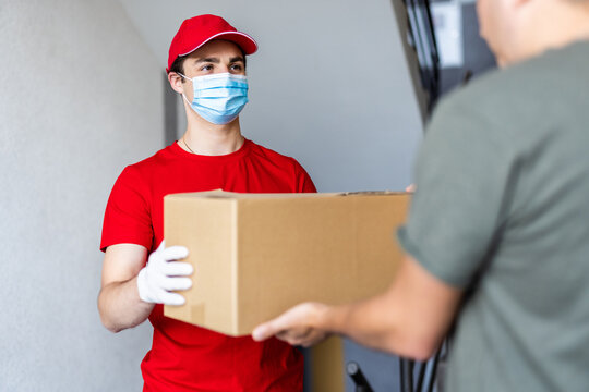 Postman, Deliveryman Wearing Mask Carry Small Box Deliver To Customer In Front Of Door At Home. Man Wearing Mask Prevent Covid19, Corana Virus Affection Outbreak. Social Distancing Work Concept.