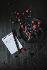 blackberries, blueberries, raspberries, fresh berries, black background, vegetarian food, notepad and pen